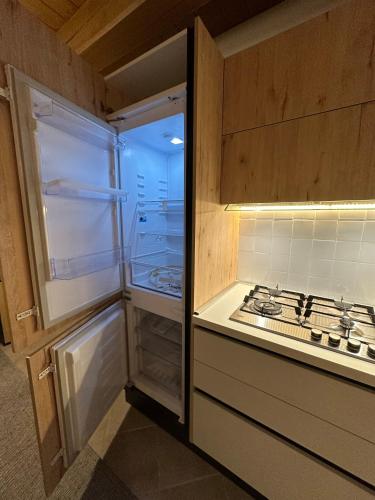 a kitchen with an empty refrigerator next to a stove at Tabia Suite Pelmo in Villagrande
