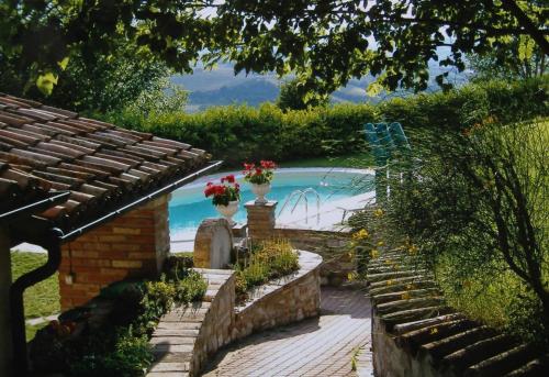 un jardín con piscina y una casa en La collina dei ciliegi, en Cagli