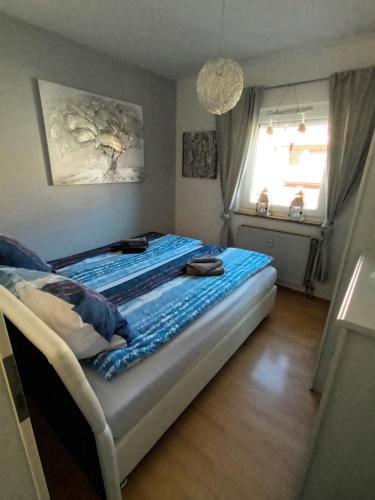 a bedroom with a bed with blue sheets and a window at Wie Daheim in Nuremberg