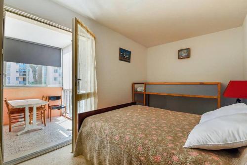 Schlafzimmer mit einem Bett, einem Tisch und einem Fenster in der Unterkunft Appart Familial Le Grau Du Roi in Le Grau-du-Roi