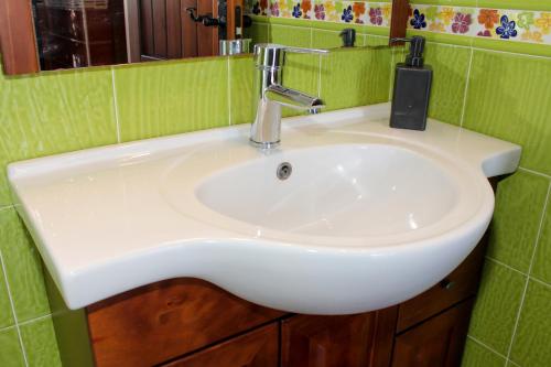 een witte wastafel in een groene betegelde badkamer bij Casa Rural Caminito del Rey in Alora