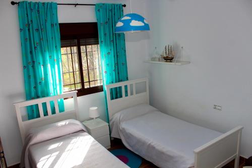 two twin beds in a room with blue curtains at Casa Rural Caminito del Rey in Alora