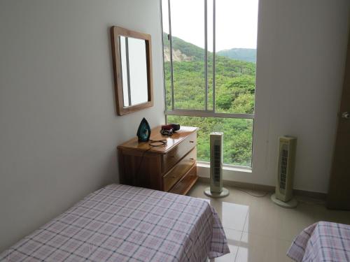 a bedroom with a bed and a dresser and a window at Espectacular y cómodo Apartamento en Girardot WiFi in Girardot