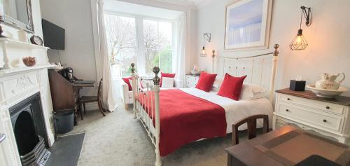 a bedroom with a bed with red pillows and a fireplace at Holbein House in Penzance