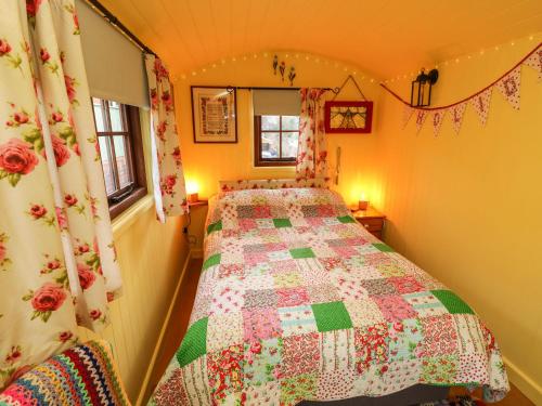 a bedroom with a bed with a quilt on it at Little Worsley and The Shepherds Hut in Ventnor