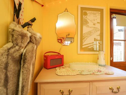a yellow room with a table with a tv on it at Little Worsley and The Shepherds Hut in Ventnor