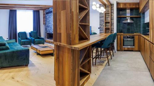 a kitchen with a long wooden bar with green chairs at Aparthotel Poljice in Jahorina