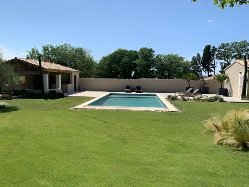 - une piscine dans une cour avec une pelouse dans l'établissement Mas des Oliviers, à Eyragues