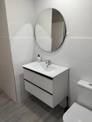 ein weißes Badezimmer mit einem Waschbecken und einem Spiegel in der Unterkunft Apartamentos Kai Santurtzi in Santurce
