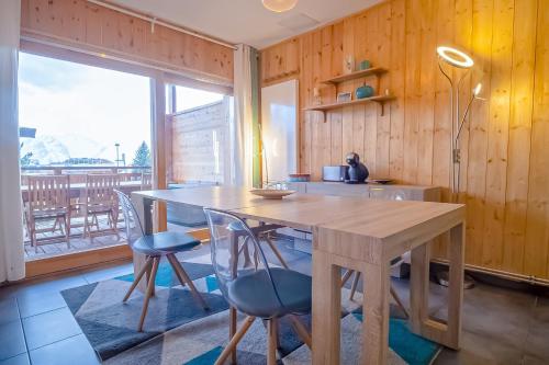 a kitchen with a wooden table and chairs and a window at Spacious apartment with terrace - Alpe d'Huez - Welkeys in LʼHuez