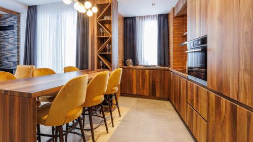 a kitchen with a long wooden table and yellow chairs at Aparthotel Poljice in Jahorina