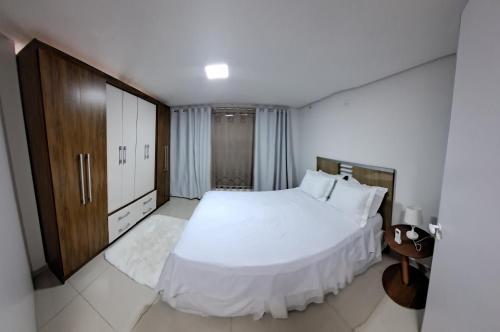 - une chambre avec un lit blanc et une armoire en bois dans l'établissement Hospedaria Maviane Executive, à Treze Tílias