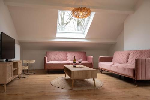 a living room with pink couches and a tv at Huize Nassau in Zelem