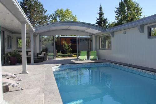 - une piscine à côté d'une maison avec une terrasse dans l'établissement La Roulotte du Domaine de Meigné, à Meigné