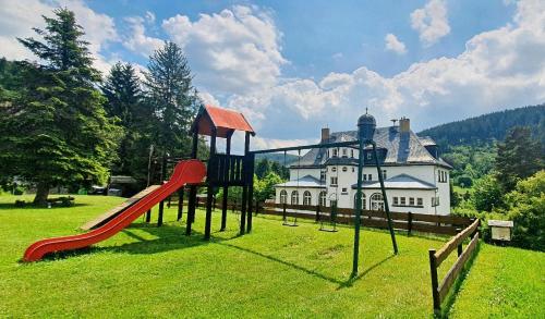 un parque infantil frente a una casa grande en Waldhotel Feldbachtal en Neuhaus am Rennweg