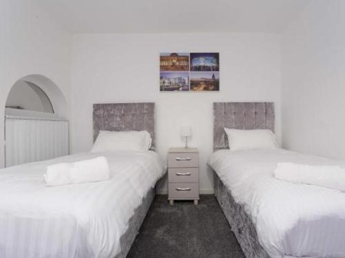 a bedroom with two beds and a nightstand between them at Nazarene apartments in Leeds in Stanningley