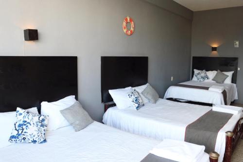 a hotel room with two beds and a clock on the wall at Hotel Las Brisas in Catemaco