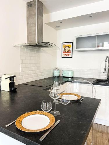 - une cuisine avec 2 assiettes et des verres à vin sur un comptoir dans l'établissement Quartier historique - Parking - Idéal Couple, à Pau