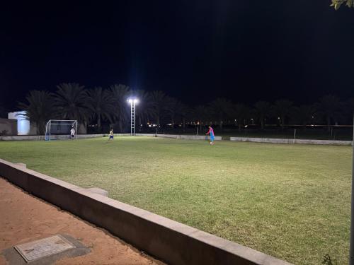 pole w nocy z ludźmi grającymi w piłkę nożną w obiekcie Al Khamail Land for Greenhostel w mieście Al Wāşil
