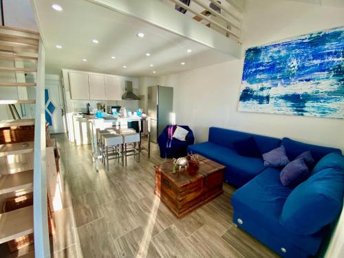a living room with a blue couch and a kitchen at Tanis Ocean Loft in Martinšćica