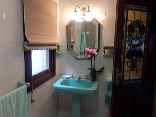 y baño con lavabo azul y espejo. en Casa Pontevella, en Amés