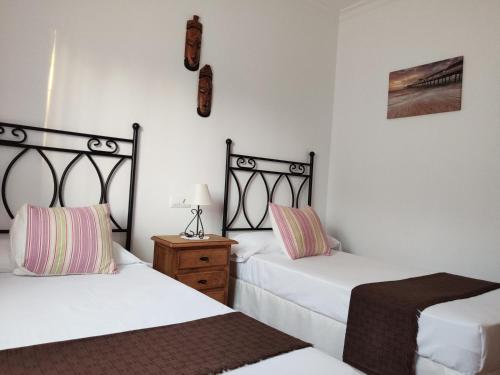 ein Schlafzimmer mit 2 Betten und einem Nachttisch mit einer Lampe in der Unterkunft Casa Rural Asgard in Chiclana de la Frontera