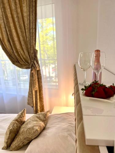 a bed with two pillows and a table with wine glasses at Villa Perla di Mare in Kranevo