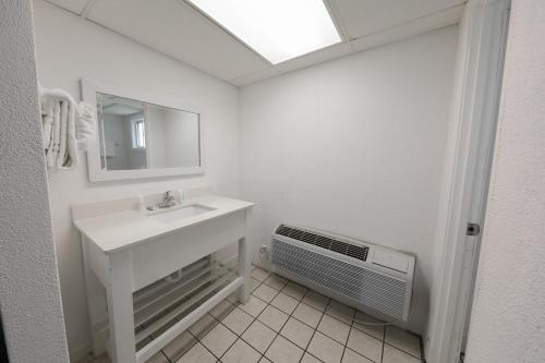 a bathroom with a sink and a mirror and a fan at Flamingo Hotel & Tower in Panama City Beach