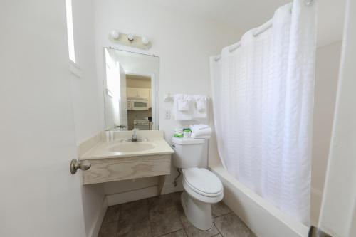 a white bathroom with a toilet and a sink at Flamingo Hotel & Tower in Panama City Beach