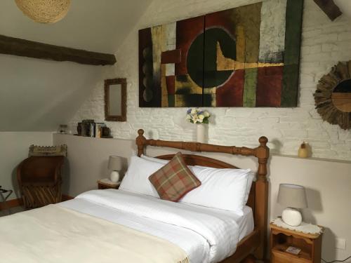 a bedroom with a bed and a painting on the wall at Le Bois Gautier in Savigny-le-Vieux