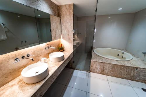 a bathroom with a sink and a tub at Garden Hotel in Campina Grande