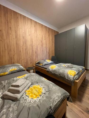 two twin beds in a room with wooden walls at Apartmán TATRAFUN in Tatranská Lomnica
