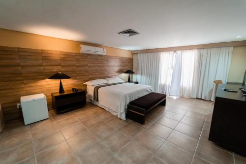 1 dormitorio con 1 cama, 1 mesa y 1 lámpara en Garden Hotel, en Campina Grande