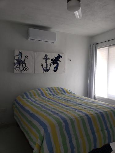 een slaapkamer met een bed met een kleurrijk gestreept dekbed bij Departamento cómodo y hermoso a mts de la playa in San Crisanto