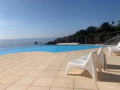 a row of white chairs sitting next to the ocean at Petit coin de paradis sur la mer in Saint-Raphaël