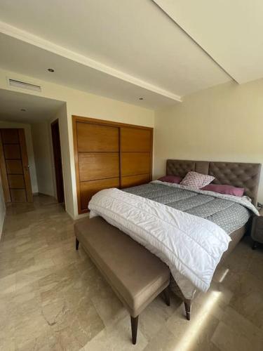 ein Schlafzimmer mit einem Bett und einer Bank darin in der Unterkunft Appartement avec jacuzzi privé in Bouznika