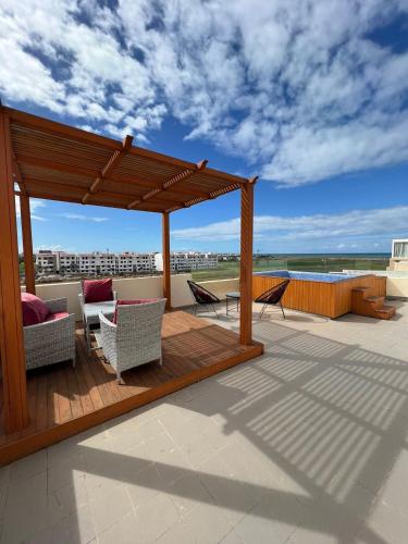 eine Holzterrasse mit Stühlen und einem Pavillon auf dem Dach in der Unterkunft Appartement avec jacuzzi privé in Bouznika