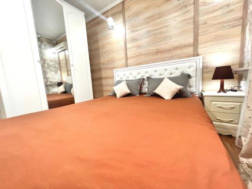 a bedroom with a large bed with an orange blanket at Sport Hotel Terra in Ustʼ-Kamenogorsk
