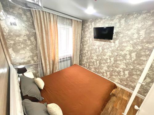 a small room with a bed and a tv on a wall at Sport Hotel Terra in Ustʼ-Kamenogorsk