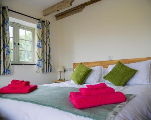 ein Schlafzimmer mit zwei roten Kissen auf einem Bett in der Unterkunft The Tack Room at Castle Chase Ayston 