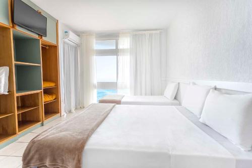 a white bedroom with a large bed and a window at Samba Laguna Tourist Hotel in Laguna