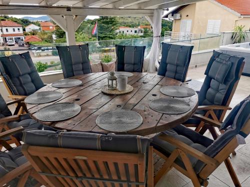Une table et des chaises en bois sont disponibles sur la terrasse. dans l'établissement Penhaus apartman Angelus Drage, à Pakoštane
