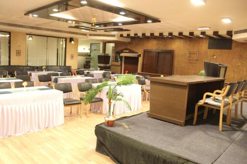 a conference room with a podium and tables and chairs at Hotel The Grand Chandiram in Kota