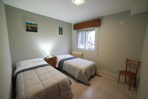 1 dormitorio con 2 camas, silla y ventana en Hostal Molgas en A Medorra