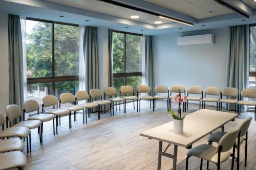 a room with chairs and tables in a room with windows at Jacob Ohalo Kinneret in Kinneret