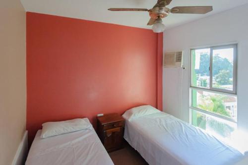 twee bedden in een kamer met een rode muur bij Departamento en Santiago del Estero in Santiago del Estero