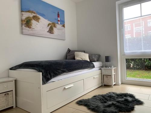 a bedroom with a white bed with a black blanket at Apartment Sonnenrauschen in Emden