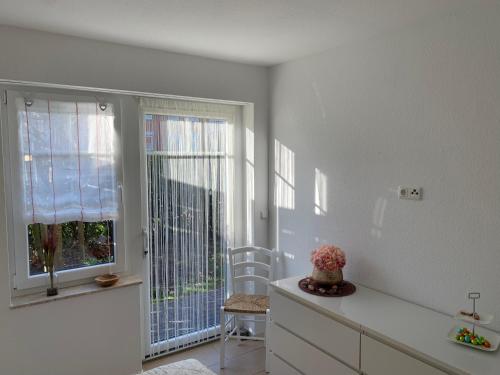 eine weiße Küche mit einem Fenster und einem Stuhl in der Unterkunft Apartment Sonnenrauschen in Emden