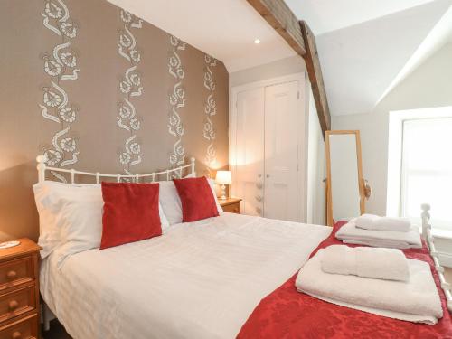 a bedroom with a white bed with red and white pillows at Willow Cottage in Alnmouth