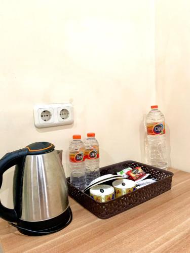 a tray with a tea kettle on a counter with water bottles at Al-Kiswah Syariah Guest House in Blitar